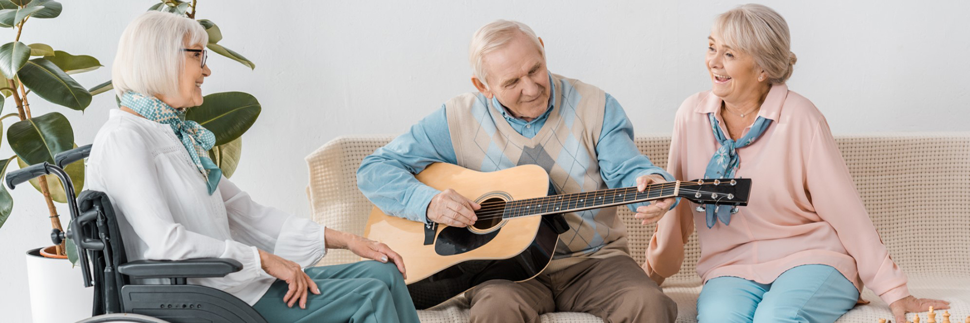 three people sitting with man in middle playing guitar
